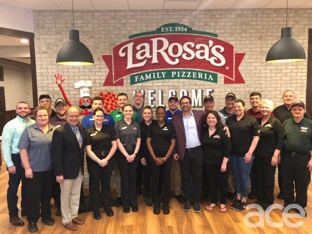 LaRosa's: large group of people standing in front of a brick wall with a logo