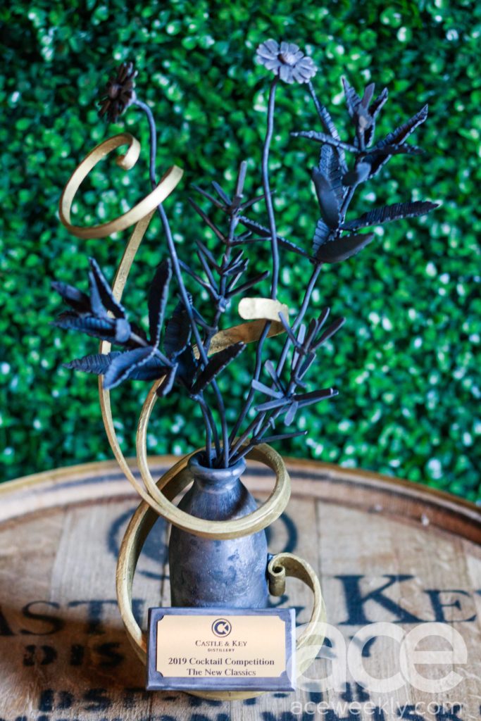 Castle & Key: a trophey on a bourbon barrel with greenery behind it