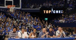 rupp arena: group of people sitting at a table with a big crowd behind them