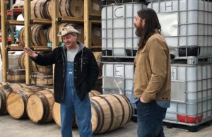 Moonshiners: two men standing in front of barrels talking