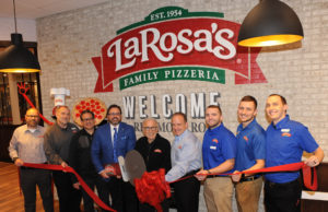 group of people standing in front of a LaRosa's sign with ribbon