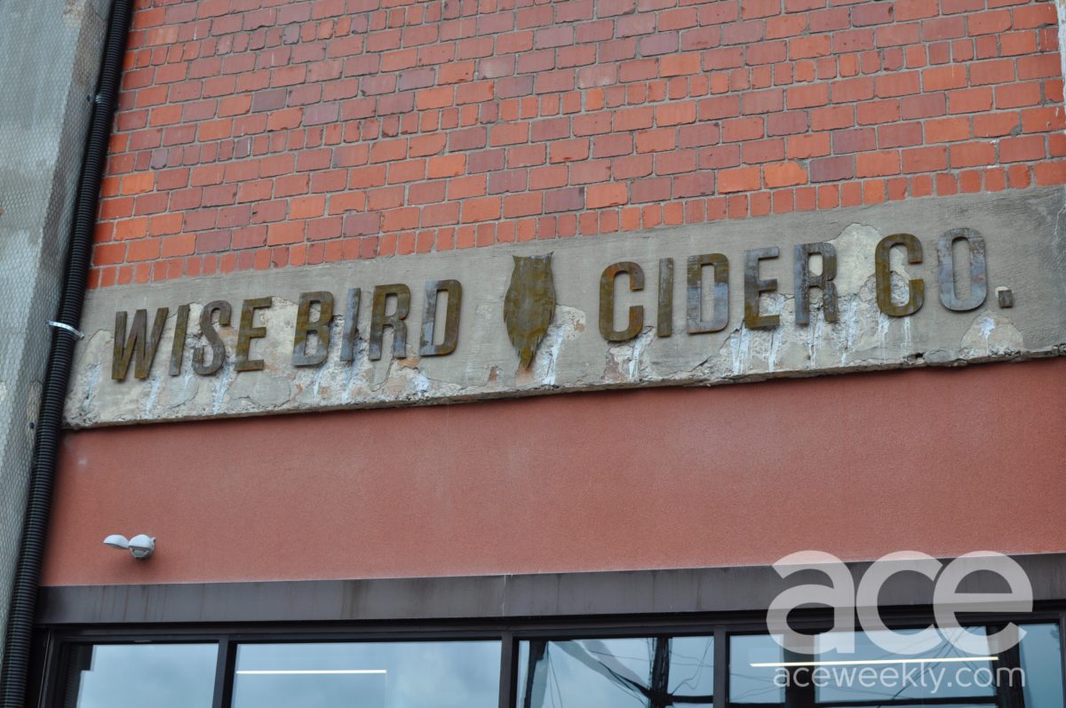 sign on a brick building that says wise bird cider co.