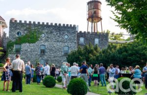Castle & Key: outside shot of people in a garden and a tall water tower and stone building behind them