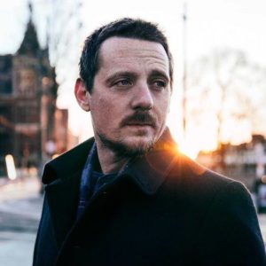 Sturgill Simpson: man in a black coat with the sun behind him